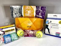 Front view showing the Zumba Live It Up box with 3 DVDs, 2 yellow toning sticks, resistance band packaging, and Go Fit power loops bands.