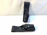 Two black leather belt holsters, showing front and side views with snap closures and belt loops.