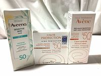 Photo showing the three new sealed boxes of Avene and Aveeno mineral sunscreen creams with SPF 50, labeled for sensitive skin and tinted compact formulas.