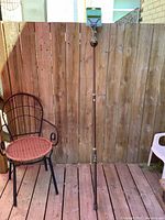 Full view of the Primos Trigger Stick Gen 2 bipod standing upright against a wooden fence with a nearby chair for scale.