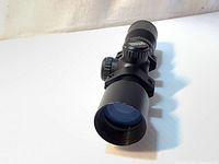 Front perspective of black Excalibur Dead Zone crossbow scope showing the 32mm objective lens with blue anti-reflective coating and mounting rings attached.