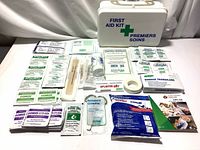 Shows full layout of all contents inside the first aid kit including bandages, cotton swabs, tongue depressors, scissors, cold pack, adhesive tape and antiseptic wipes.
