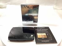 Silver boxed Lancôme Color Design palette outer packaging with compact black plastic palette and informational insert booklet laid in front.