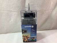 Front view of Safari 5D camera in its clear waterproof housing, placed on its original box showing product branding and features.