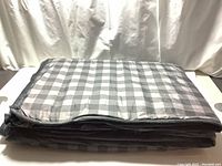 Folded grey dual-sided weighted blanket with visible checkered pattern side on top.