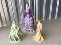 Three Coalport porcelain figurines Sarah, April, Jennifer, shown from front on a flat surface with industrial background.