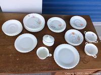 Assortment of Mikasa bone china plates, bowls, cups and small covered dish with floral patterns arranged on table, showing overall lot contents and condition.