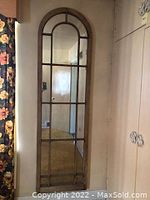 Full length view of large arched wall mirror installed vertically, showing its height and multi-pane design.