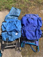 Two external frame hiking backpacks placed on the ground outside showing overall shape and color