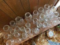 Top view showing 27 Ball Mason jars arranged on a wooden surface, varying in size and height, all clear glass.