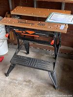 Overall view of Black & Decker Workmate 400 portable workbench showing wooden top boards, metal frame, and paper instruction manual laid on top.