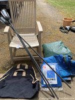 Plastic folding lawn chair, tarps, three black metal tiki torches
