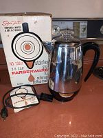 Photo showing Farberware stainless steel coffee maker next to its original box with product details