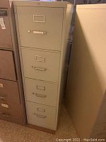 Front view of beige 4-drawer metal file cabinet, showing handles and label holders.
