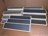 Group of five kitchen shelf organizers with white frames and black ribbed platforms in a box