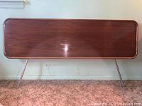 Front view of walnut veneer wood headboard with rounded corners and slender metal legs