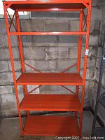Front view of the orange metal utility shelf showing all four shelves and sturdy metal construction.