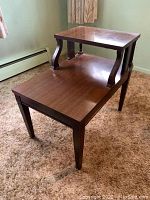 Mahogany mid century step end table shown from an angle displaying the stepped design and curved supports.