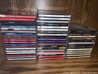 Photo showing many music CDs stacked on a wooden shelf with visible titles including Chuck Mangione, Dianne Reeves, Johnny Cash, Hammers of Misfortune, Cornel West, and more.