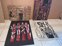 Original woodblock prints and carved woodblocks by Aaron Cobbett arranged on the floor, showing multiple pieces with figurative imagery of person and flowers