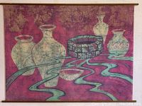 Full view of the signed batik hand dyed wall art showing abstract vases, a bowl, and flowing lines on a reddish-purple background.