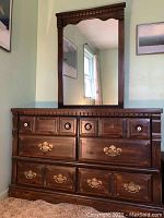 Full view of wooden dresser with attached mirror, showing six drawers with a combination of enamel knobs (top) and brass pulls (bottom).