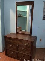 Full view of the vintage wooden dresser with attached rectangular mirror in matching wood frame. Shows brass drawer pulls and accents.