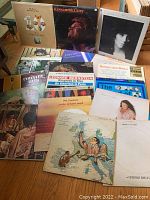 Photo showing multiple vintage vinyl LP records with visible album covers including Glen Campbell Live, Spandau Ballet Journey to Glory, and others arranged on a wooden floor.