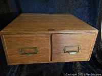 Front view of two drawer wooden card catalog showing the brass label holders and drawer pulls.