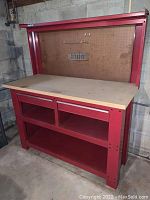 Red metal workbench front view showing countertop, two upper drawers/cubbies and lower shelf