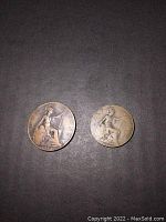 Photo showing two antique coins, a 1913 penny and a 1915 half penny, placed side by side on a dark surface.