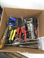 Box of assorted hand tools including screwdrivers, pliers, wire strippers, tape measure, and box cutters