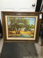 Framed oil painting leaning against a door, shows full artwork and frame with a carved wood design.