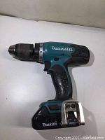 Side view of Makita cordless drill with battery attached, showing brand and model details.
