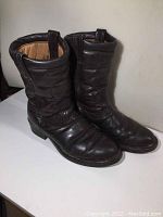 Pair of dark brown men's leather Boulet boots, showing front and side views with wrinkled leather texture, pull tabs, rounded toe, and minor wear visible.