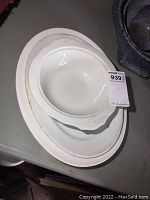 Three off-white ceramic serving pieces stacked: a large oval platter with embossed floral rim (Johnson Bros), a smaller oval platter and a serving bowl (Meakin)