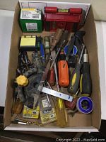 Photo showing assorted screwdrivers, a red magnetic level, chalk reel, and other hand tools in brown tray