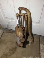 Full side view of vintage cast iron Beatty Bros. Limited Canada hand pump showing handle, body and base with aged rust.