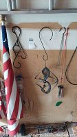 American flag on wooden pole with five different metal wind chimes hanging on wall