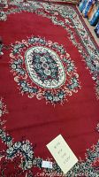 Photo showing full view of the rectangular floral design area rug with a central floral medallion on a red background and floral border.