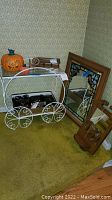Full view of metal cart with glass top and wheels, carved wood mirror with crack, stained glass applique mirror, and carved wooden item on floor.