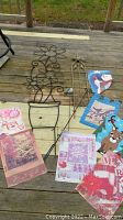 Lot items displayed on wooden surface with garden flags featuring snowman, reindeer, piglet, and winter themes alongside metal trellises shaped as flowers and star motifs.