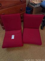 Two deep red portable floor chairs positioned side by side, showing overall appearance and structure.