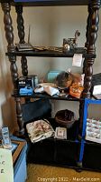 Photo of shelving unit displaying various items including silver plated serving pieces, Braun shaver box, vanity boxes, and other personal care items