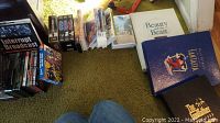 Photo of assorted VHS and DVD movie titles on carpet, including notable box sets and single cases.