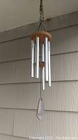 Full view of the hanging wood and metal wind chimes showing six metal tubes, wooden top, and bottom wind catcher.