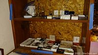 Wide view of shelf with multiple trays and boxes containing assorted jewelry pieces including rings, bracelets, and necklaces.