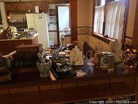 Wide view of table with vintage books, Buick model car, three Fenton angel figurines, Royal Doulton clock, and glass items