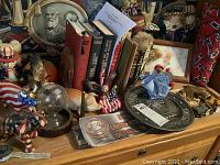 Top view showing Uncle Sam nutcracker, resin and ceramic figurines with American flag themes, and vintage books behind them.