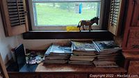 Stack of several issues of Civil War Times magazines arranged on a wooden surface under a window with a small horse figurine